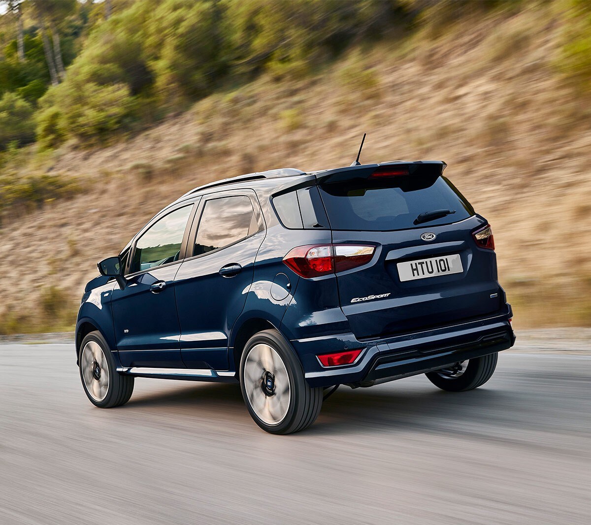Ford EcoSport in Blau. ¾-Heckansicht. Auf einer Landstraße fahrend.