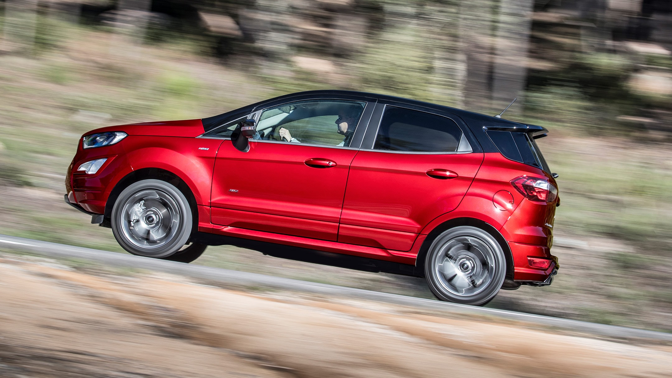 Ford Ecosport in Rot. Seitensicht. Fahrszene an einem steilen Berg