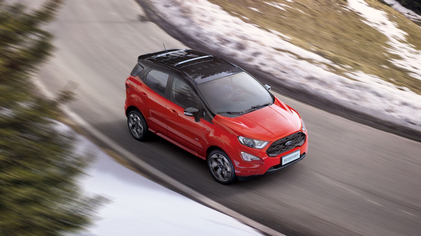 Ford EcoSport in rot. Dreiviertelansicht. Fahrend auf einer Landstraße mit Schnee