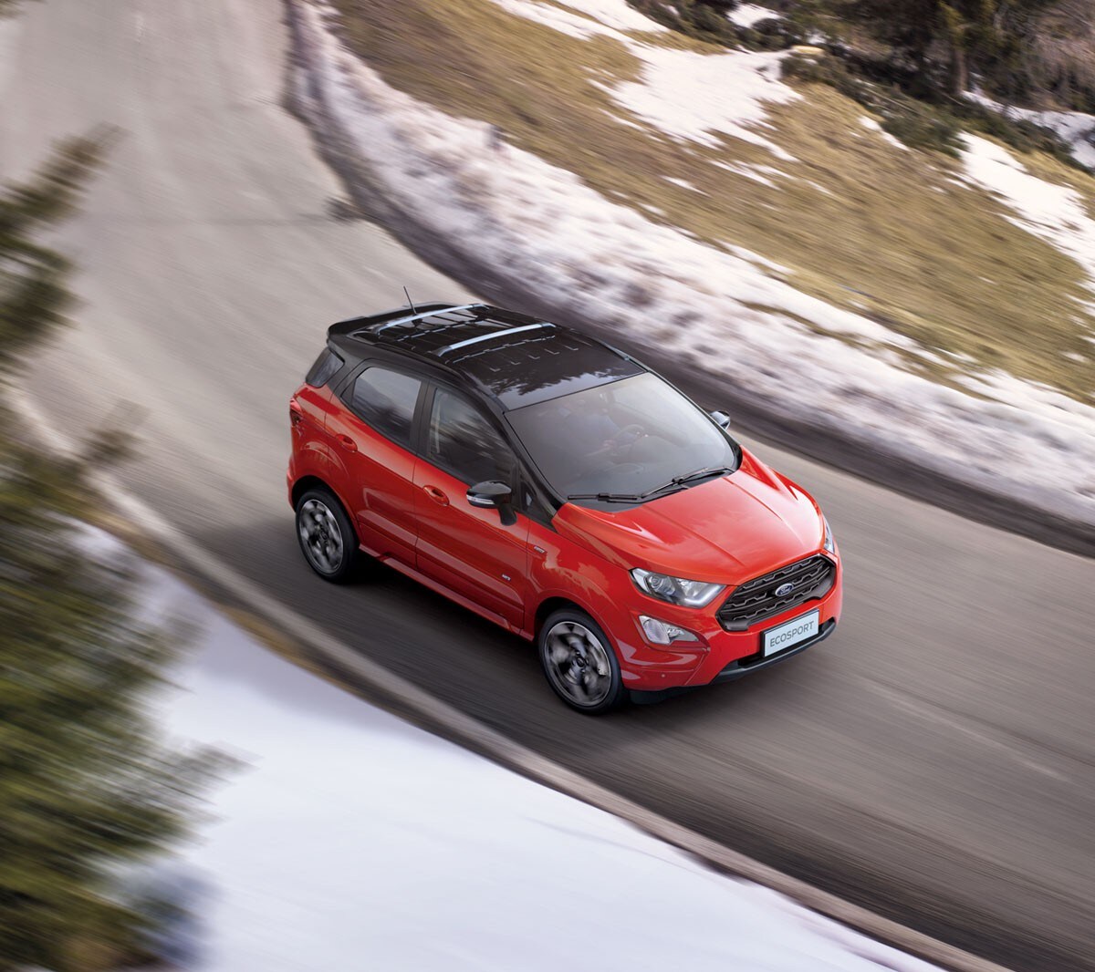 Ford EcoSport in Rot mit schwarzem Dach. ¾-Frontansicht von oben. Auf einer Landstraße fahrend