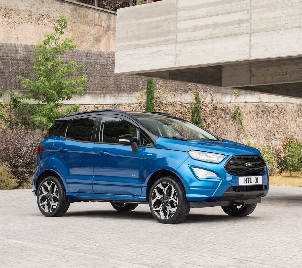 Ford EcoSport in Blau. ¾-Frontansicht. Parkend vor einem modernen Gebäude