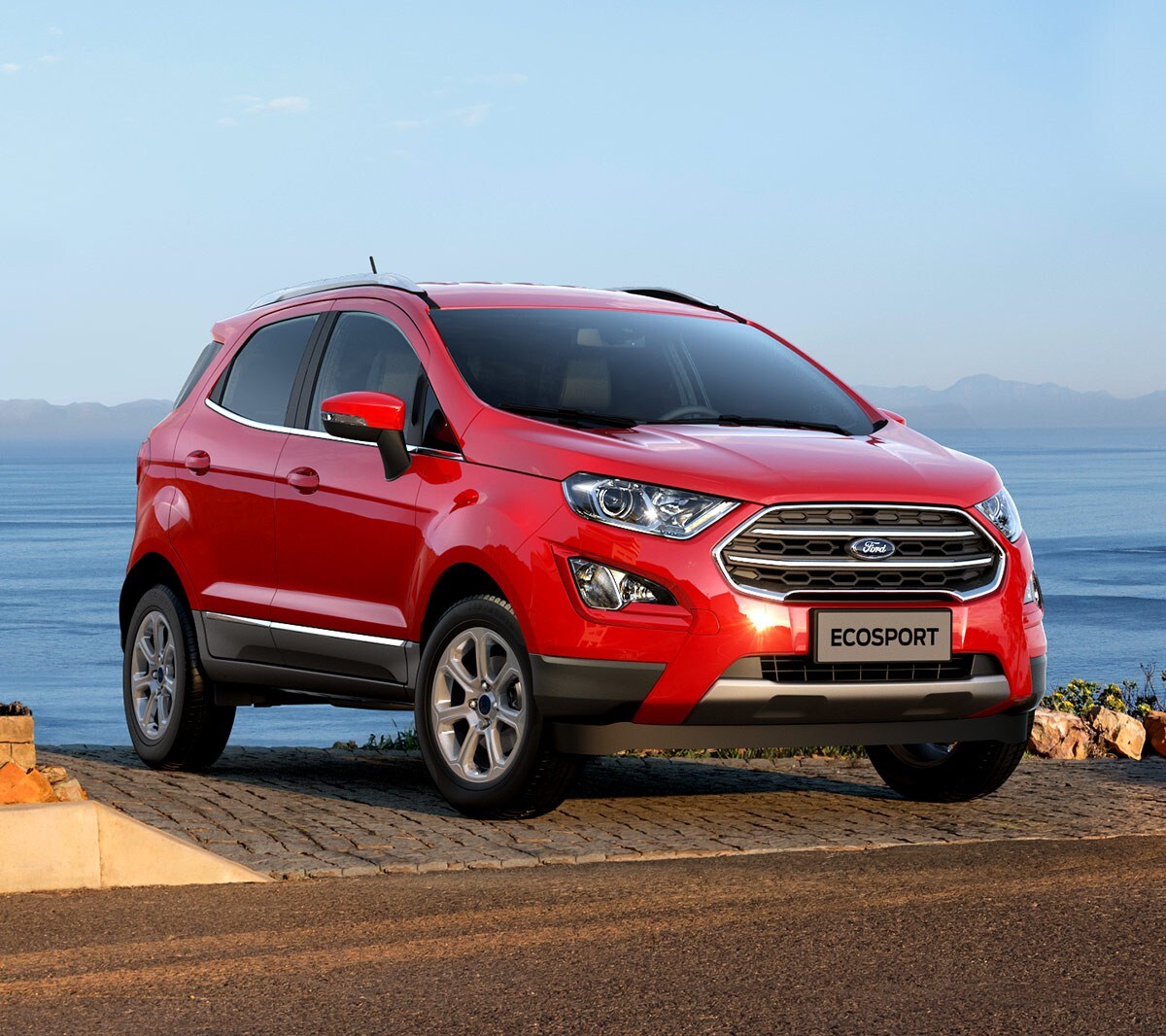 Ford EcoSport in Rot. ¾-Frontansicht. An einer Küste mit Blick aufs Meer parkend