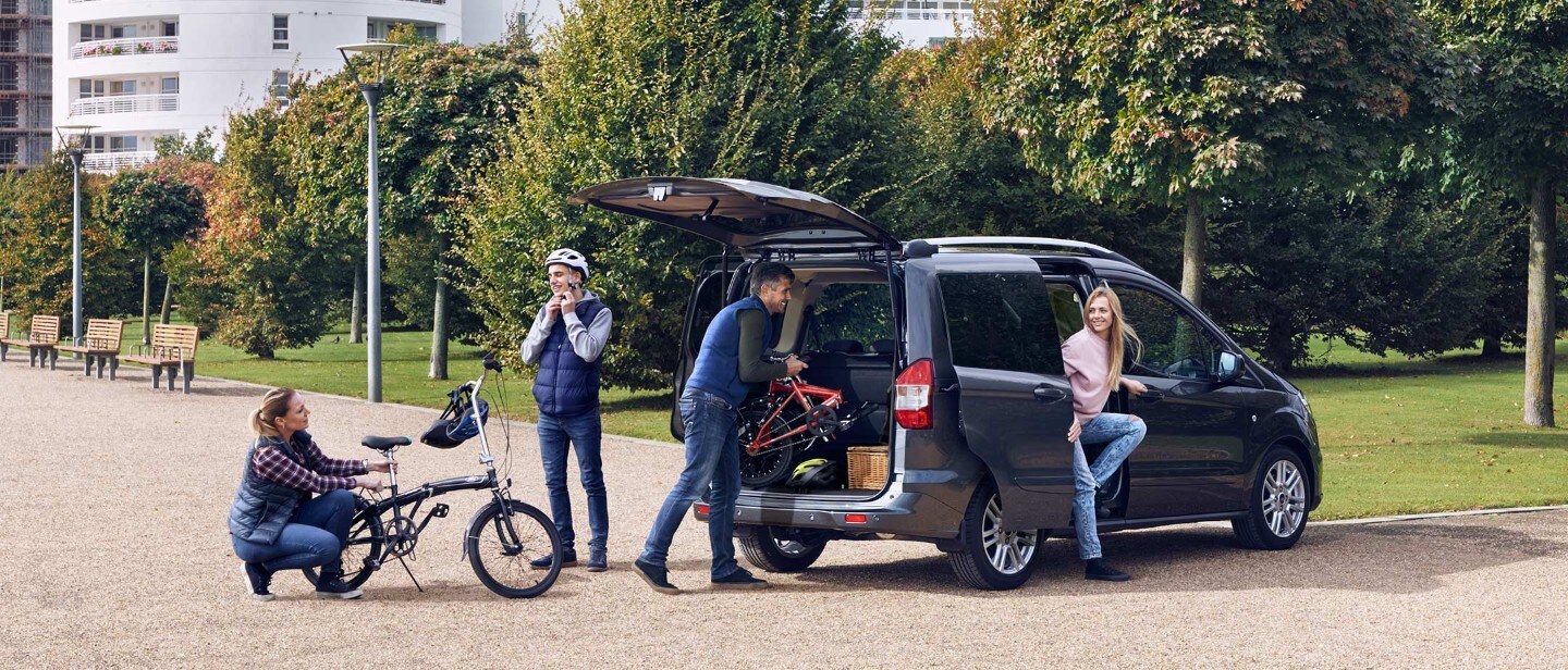 Ford Tourneo Courier parked near park with family and bicycle