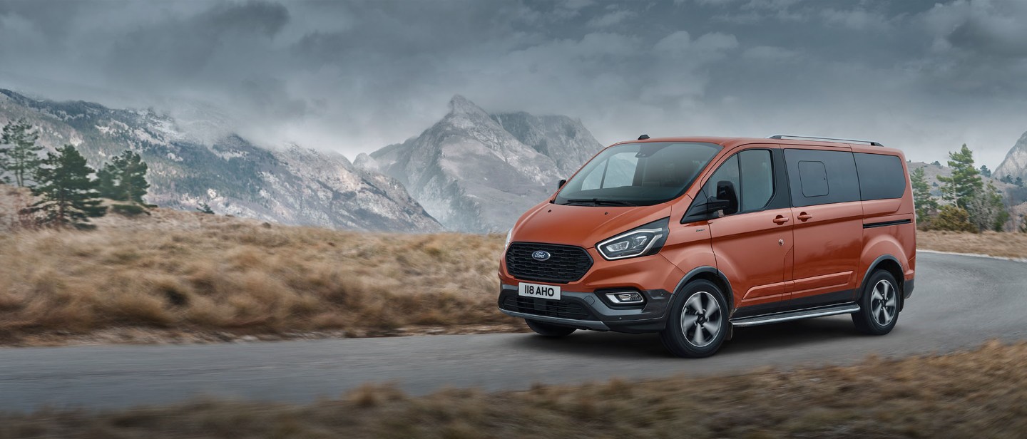 Ford Tourneo Custom Active Orange ¾-Seitenansicht fährt über Gebirgsstraße