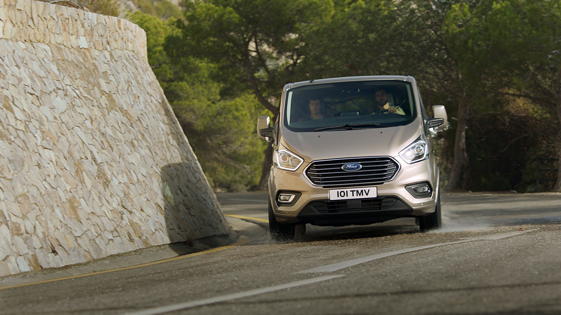 Ford Tourneo Custom Champagner Frontansicht auf Gebirgsstraße bergab in Bewegung 