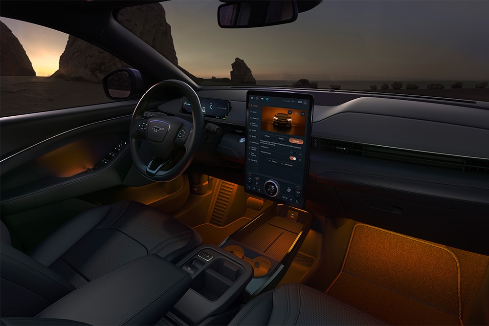 Ford Mustang Mach-E bei Nacht, mit dem 15,5-Zoll-SYNC-4-Touchscreen und auf Orange eingestellter LED-Ambientebeleuchtung