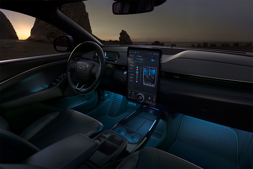 Ford Mustang Mach-E bei Nacht, mit dem 15,5-Zoll-SYNC-4-Touchscreen und der auf blau eingestellten LED-Ambientebeleuchtung.
