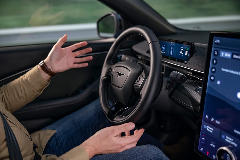 Die Hände des Fahrers schweben über dem Lenkrad des Mustang Mach-E. Dies demonstriert die BlueCruise-Technologie für autonomes Fahren.