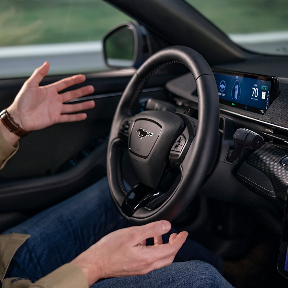 Die Hände des Fahrers schweben über dem Lenkrad des Mustang Mach-E. Dies demonstriert die BlueCruise-Technologie für autonomes Fahren.