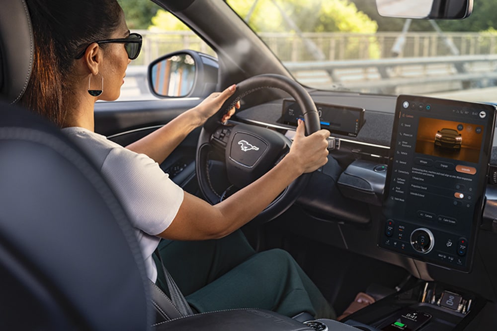 Ford Mustang Mach-E bei Nacht, mit dem 15,5-Zoll-SYNC-4-Touchscreen und auf Orange eingestellter LED-Ambientebeleuchtung