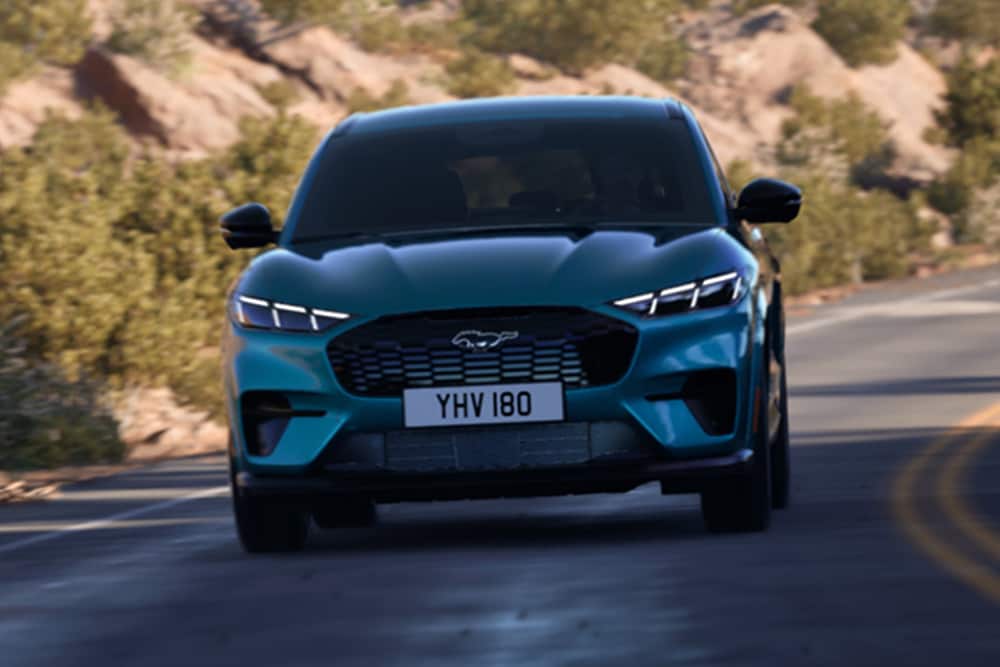 Vorderansicht des blauen Ford Mustang Mach-E, der auf einer Bergstraße fährt.