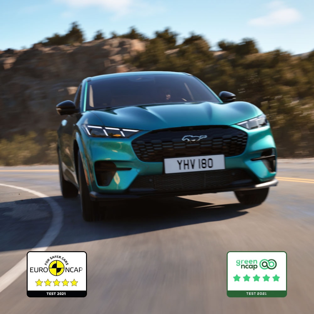 Ein Ford Mustang Mach-E GT in Adriatic Blue fährt auf einer Bergstraße.