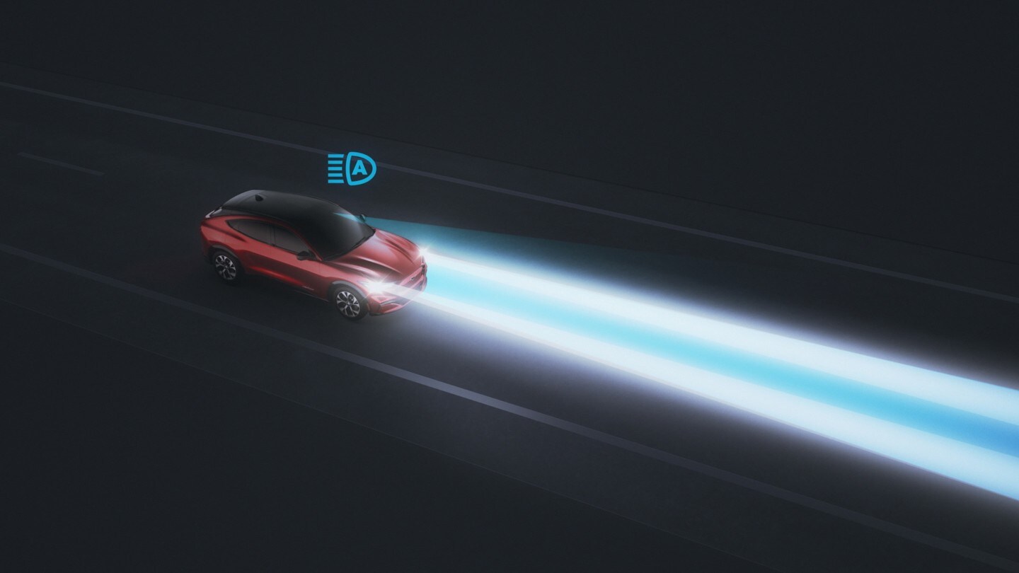 Ford Mustang Mach-E in Rot. 3/4-Frontansicht. Fahrszene bei Nacht mit Fernlicht