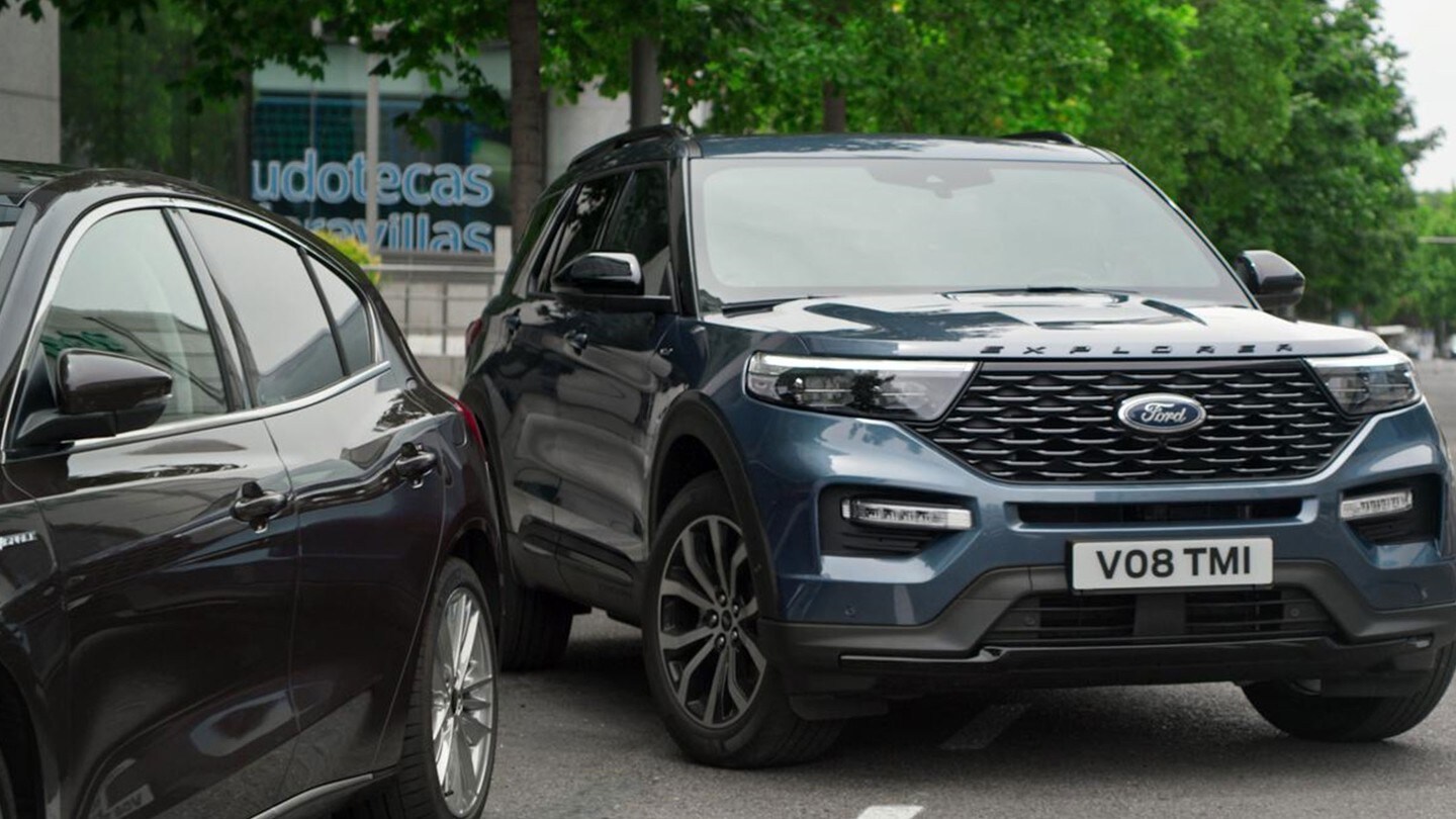 Ford Explorer Plug-in-Hybrid in Blau. Dreiviertel-Frontansicht. In enge Parklücke einparkend