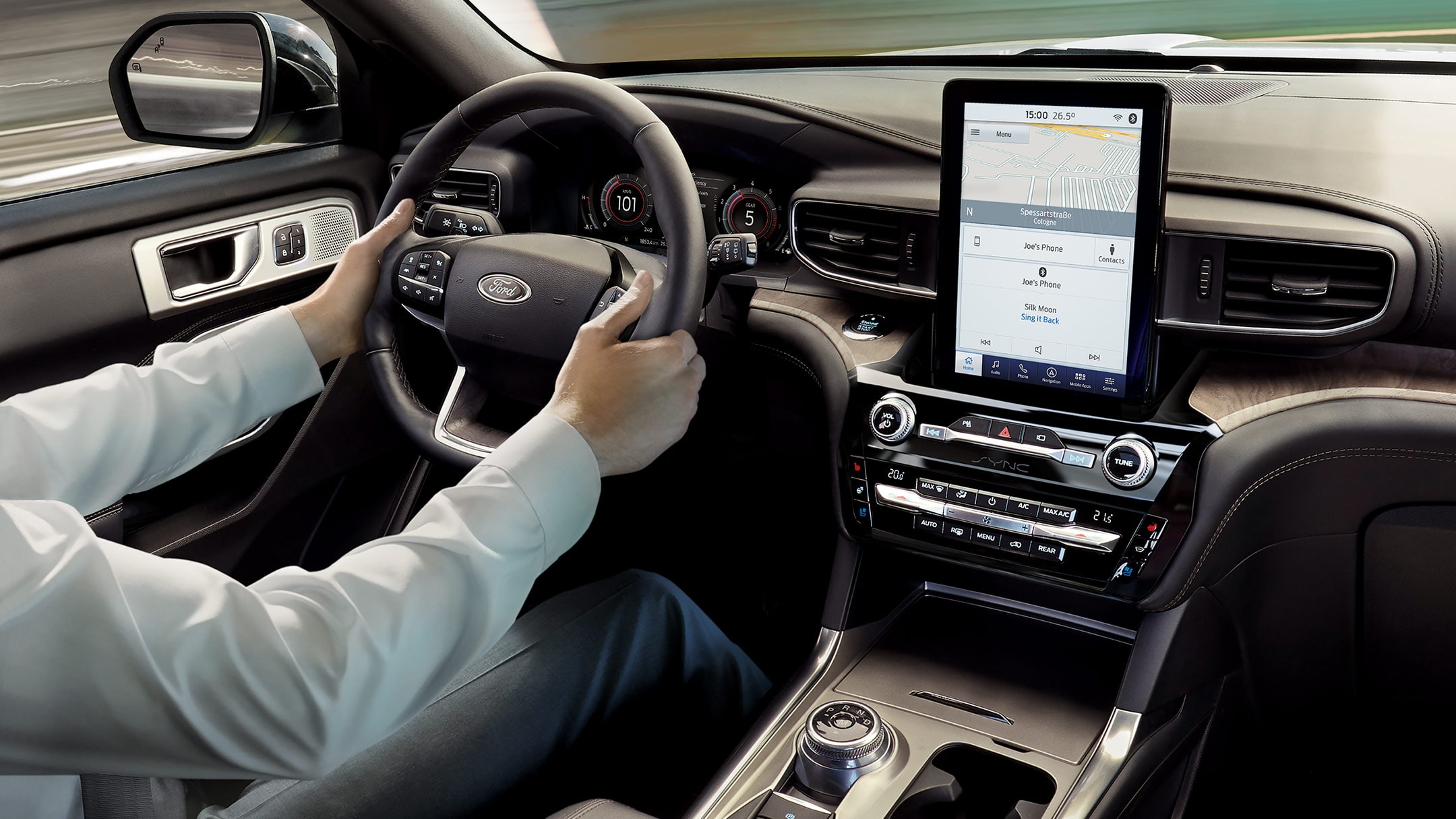 Ford Explorer Plug-in-Hybrid. Innenraum. Detailansicht Lenkrad und Mittelkonsole mit Touchscreen. Hände des Fahrers am Lenkrad