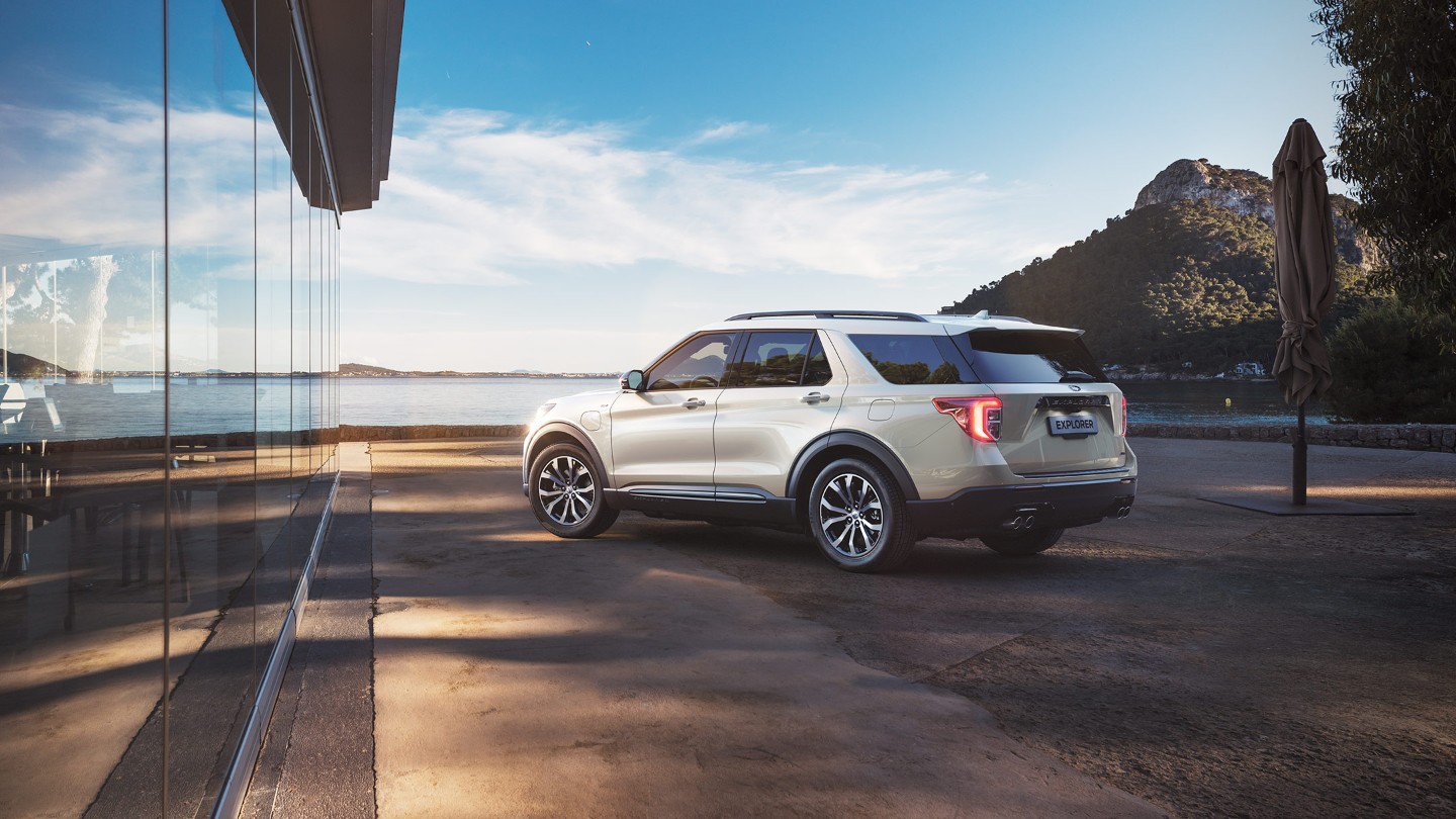 Ford Explorer Plug-in-Hybrid in Weiß. Dreiviertel-Heckansicht. Am Strand parkend