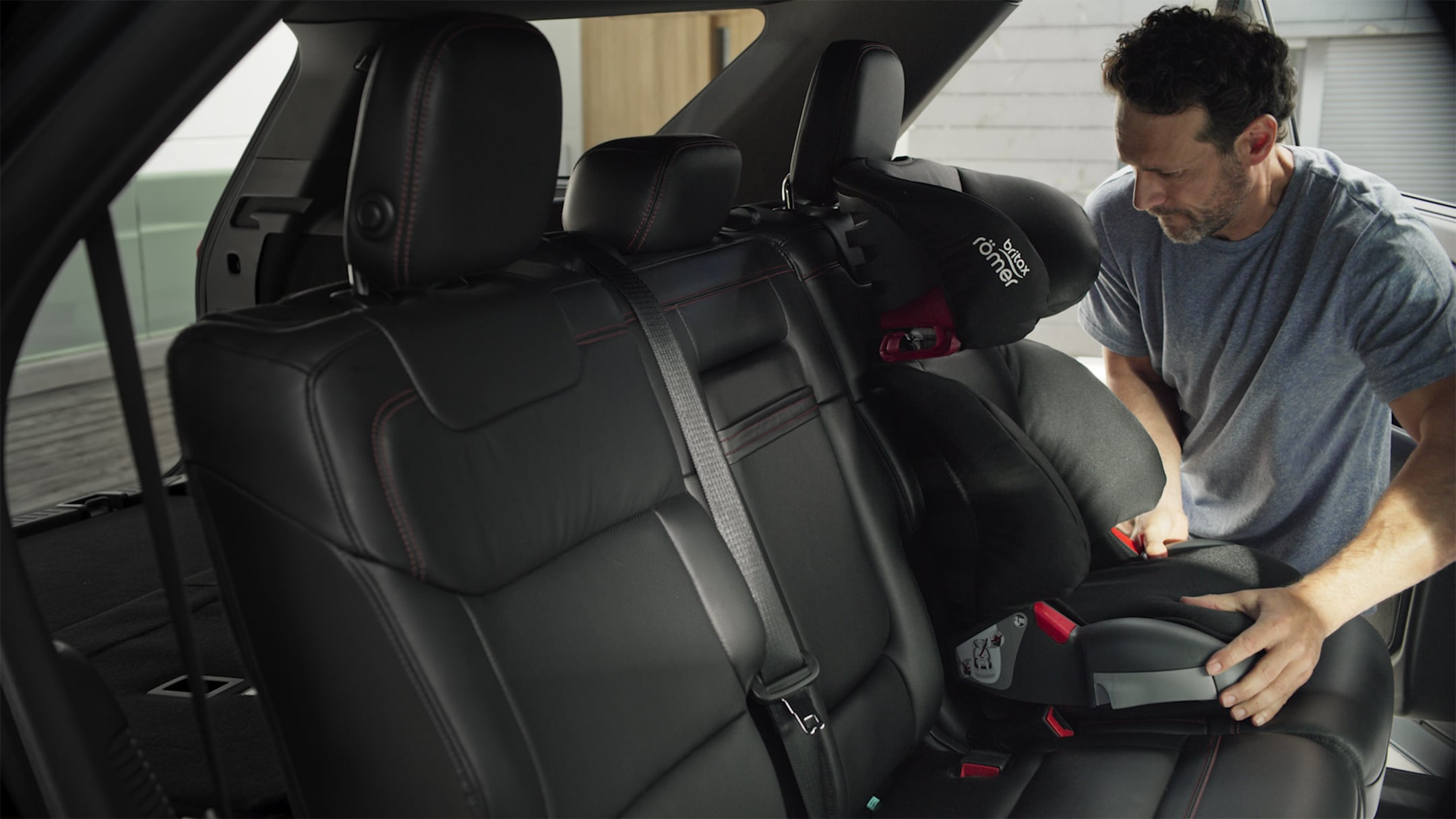 Ford Explorer Plug-in-Hybrid. Innenraum Detailansicht. Mann befestigt Kindersitz auf äußerem Rücksitz