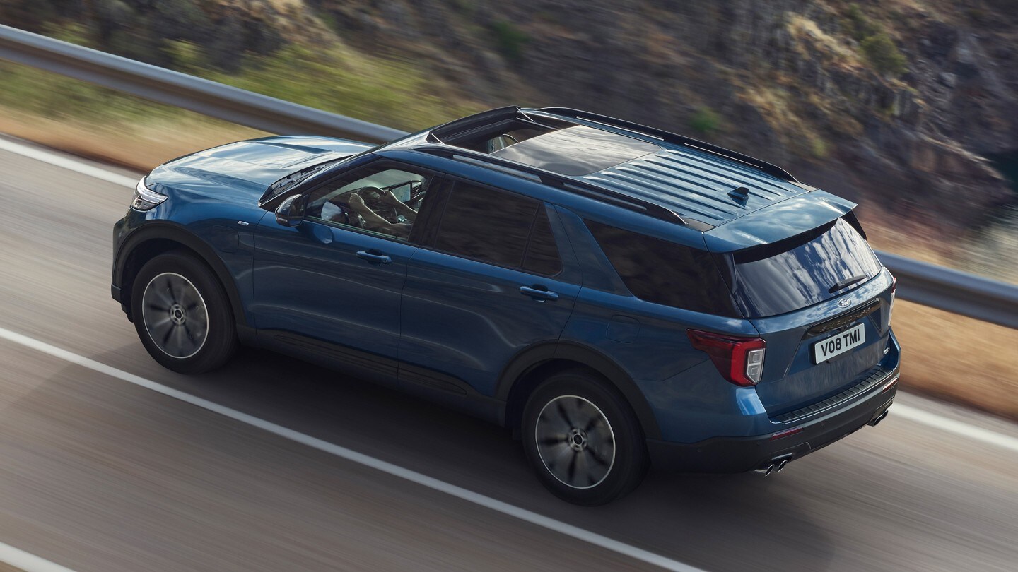 Ford Explorer in Blau. Dreiviertel-Heckansicht. Eine Straße in den Bergen bergauf fahrend