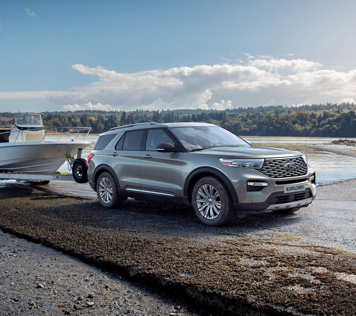 Ford Explorer Plug-in-Hybrid in Silber. Dreiviertel-Frontansicht. Mit Bootsanhänger an einem See