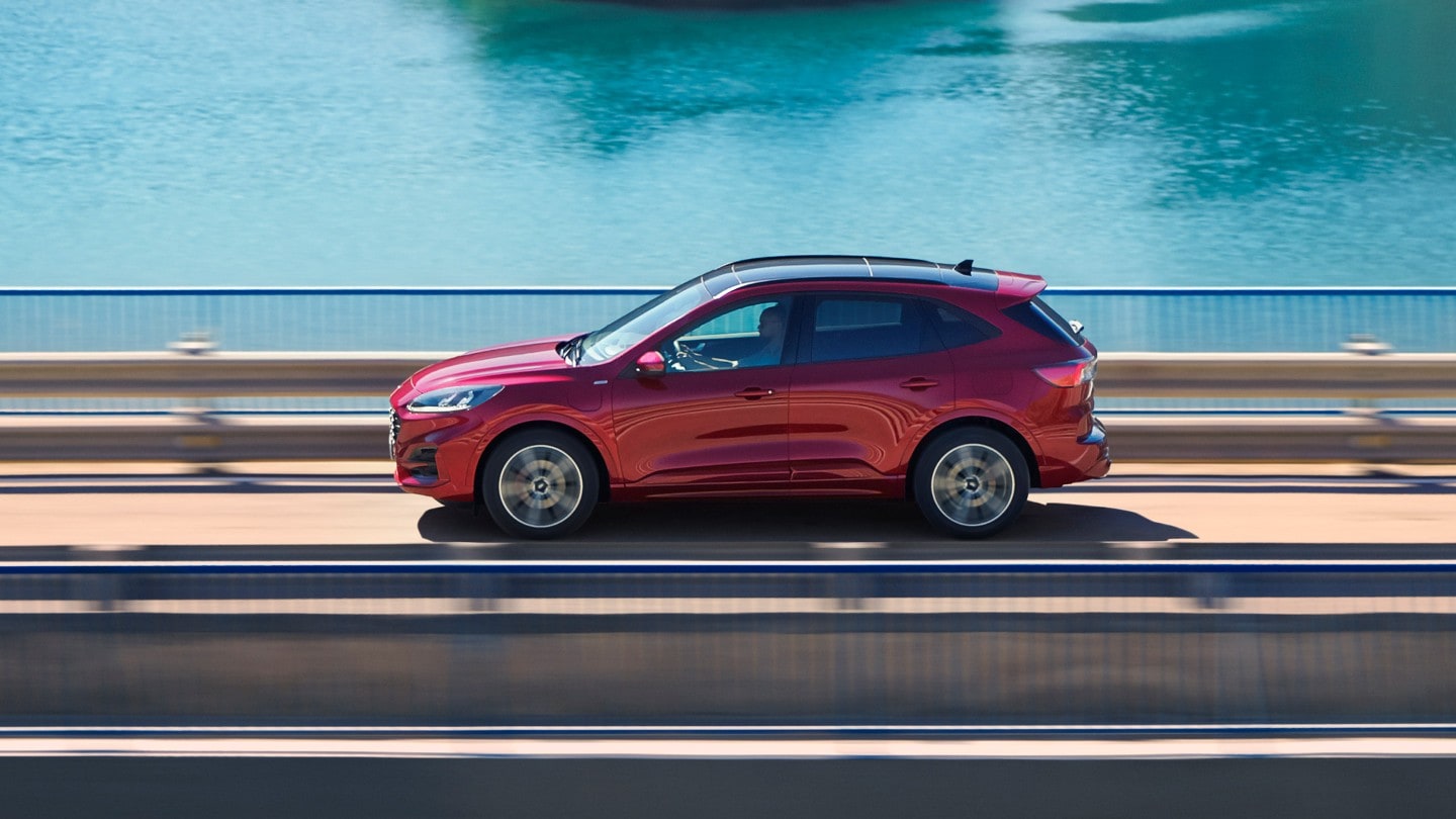 Ford Kuga Seitenansicht in Rot auf einer Brücke fahrend