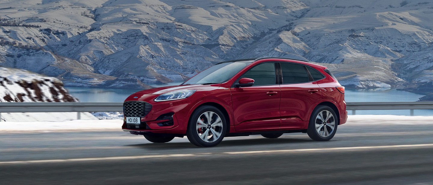Red Ford Kuga driving in front of mountains