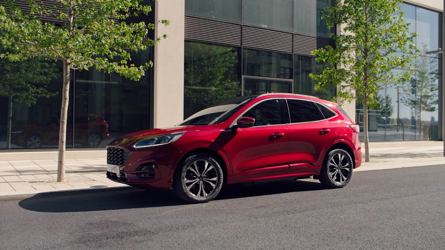 Ford Kuga in Rot. Seitensicht, vor einem Gebäude parkend