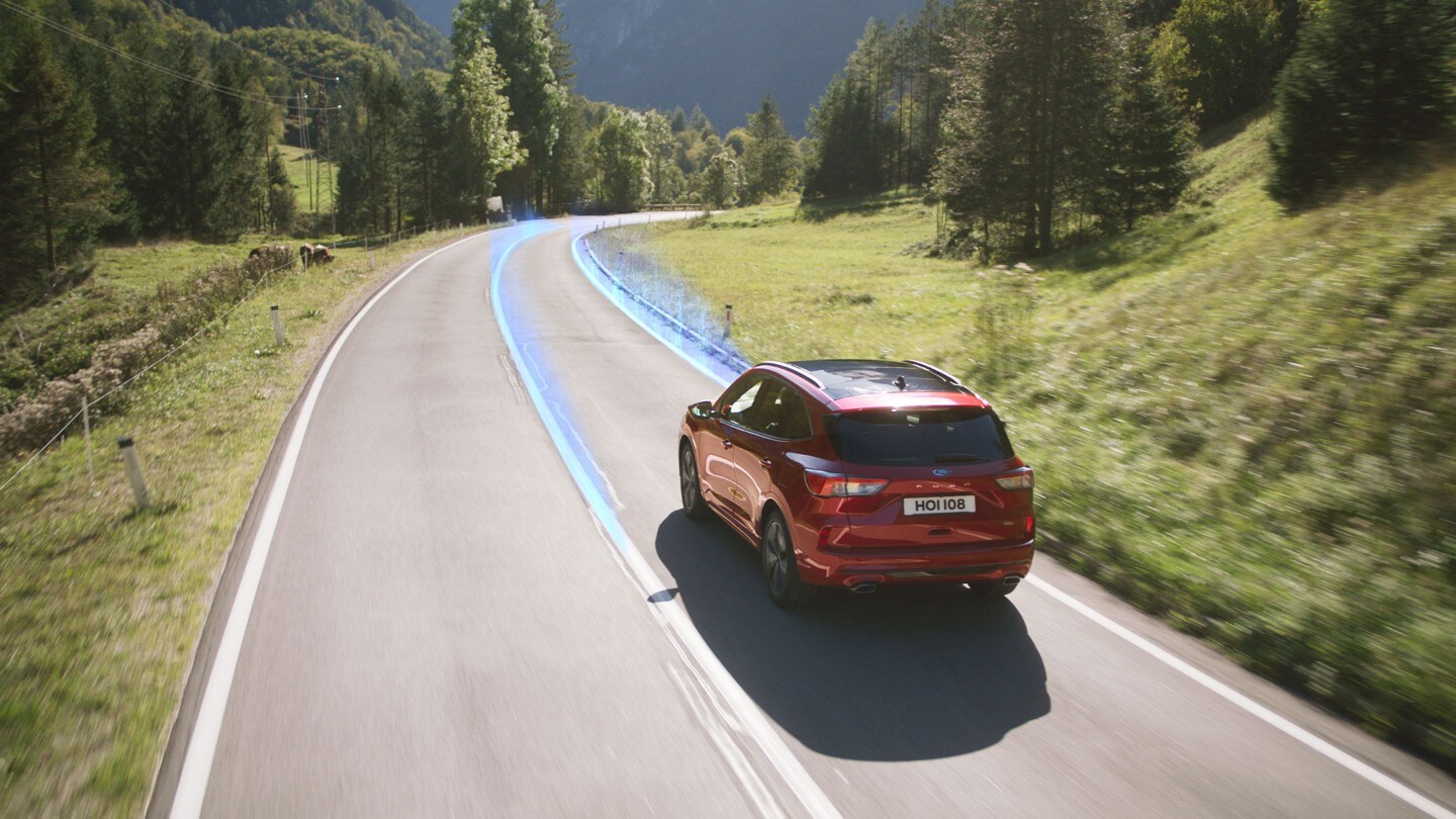 Ford Kuga in Rot. Dreiviertel-Heckansicht. Fahrszene auf einer Landstraße