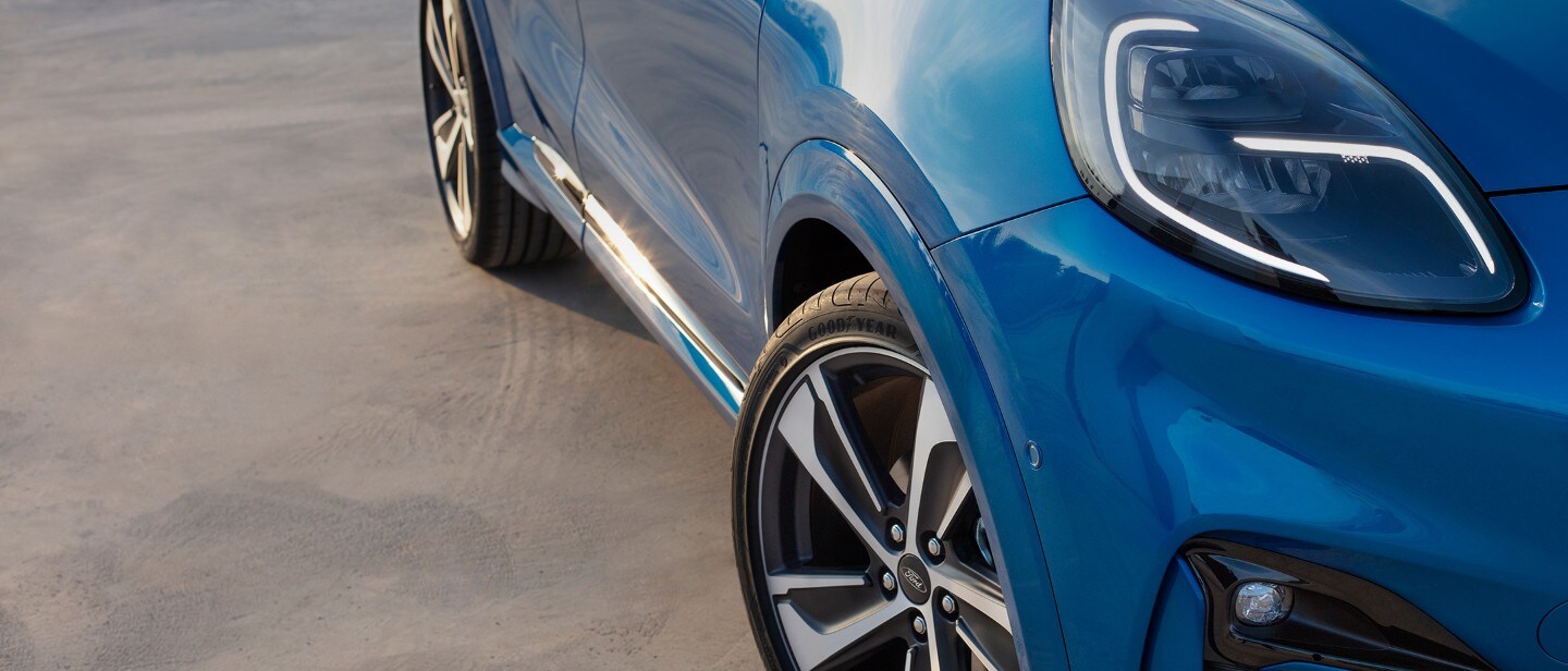 Ford Kuga ¾ Frontansicht in Blau, Detailausschnitt mit Scheinwerfer und Rädern