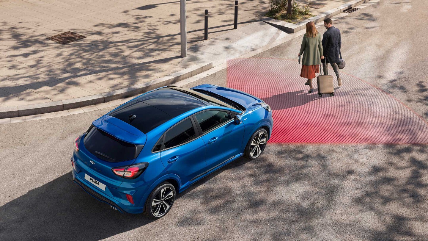Ford Puma ST-Line X in blau von hinten auf einer Straße. Davor zwei Fußgänger.