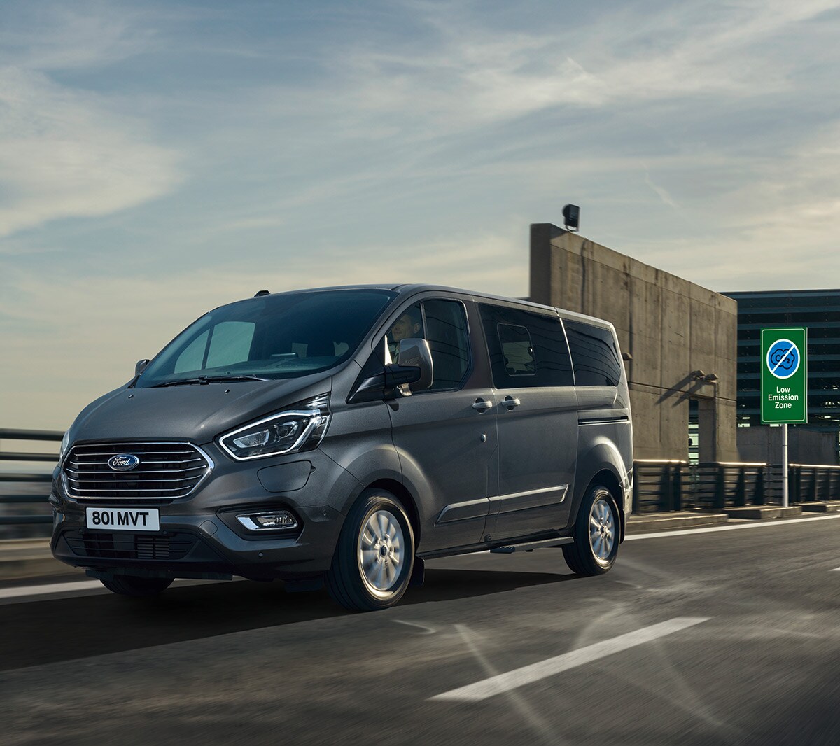 Ford Tourneo Custom Plug-in-Hybrid Grau ¾-Seitenansicht in Bewegung in grüner Umweltzone 