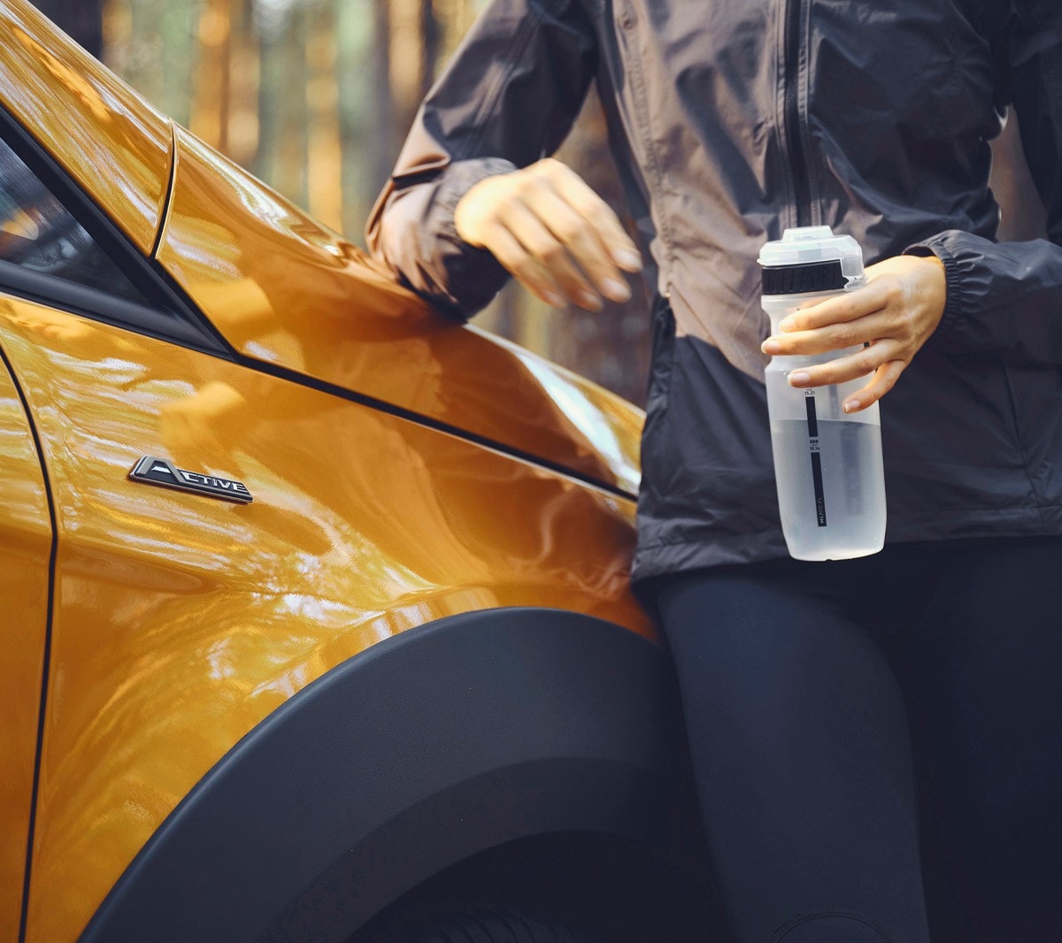 Ford EcoSport Active in Orange. Detailansicht Active Badge und Sportler mit Trinkflasche im Vordergund