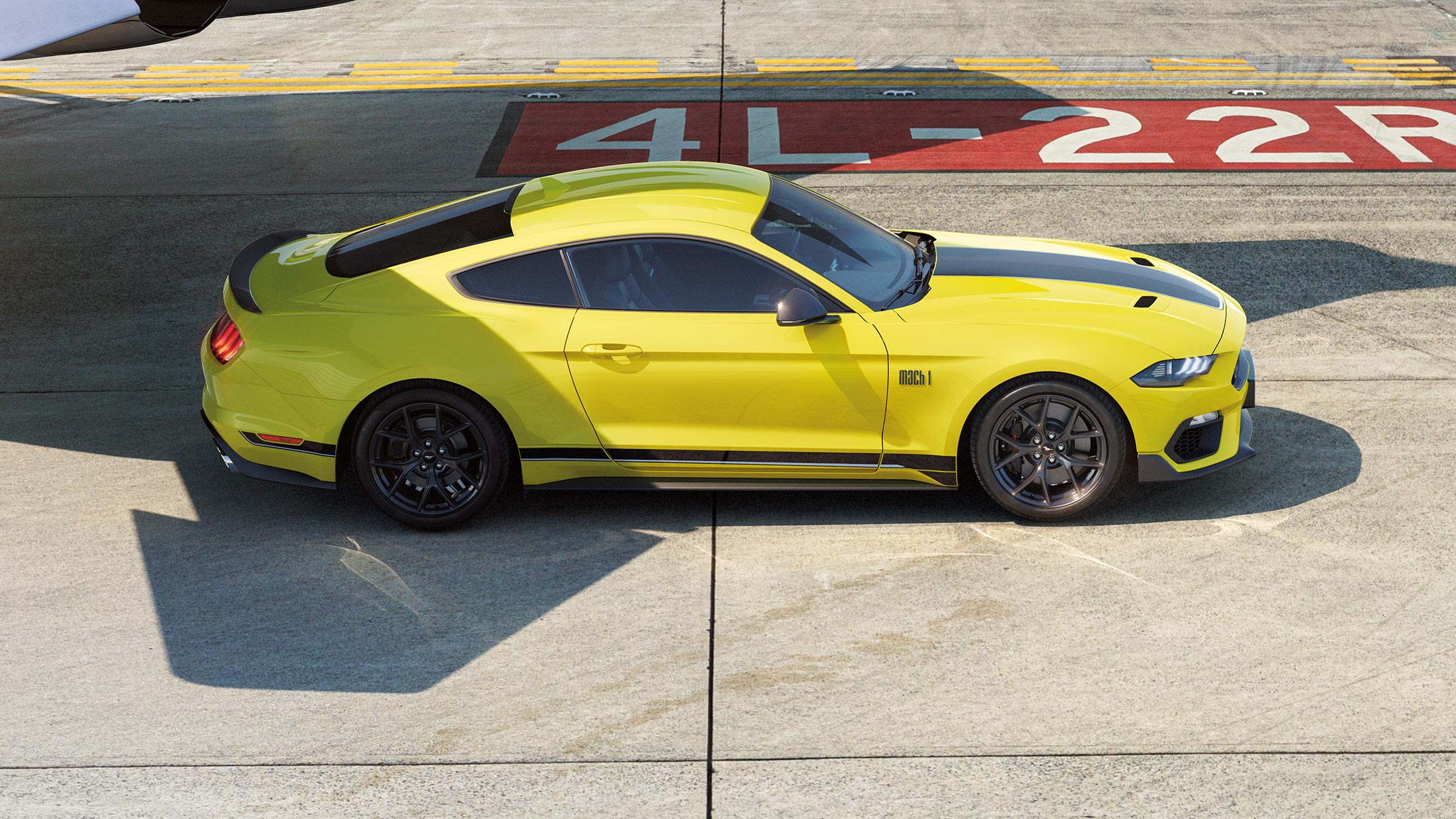 Ford Mustang Mach 1 in Gelb. Seitenansicht, auf einer Rennstrecke fahrend