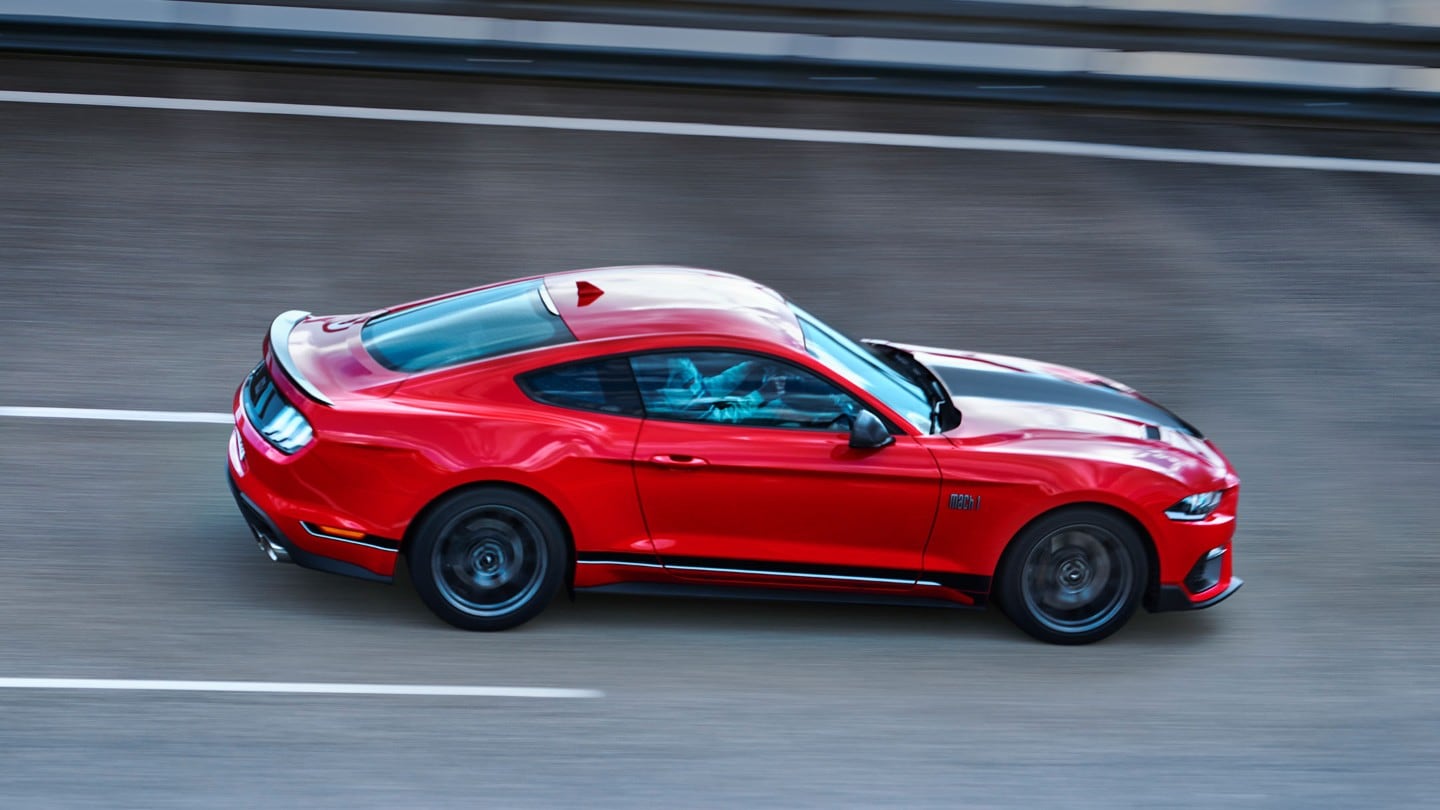 Ford Mustang Mach 1 in Rot. Seitenansicht, auf einer Rennstrecke fahrend