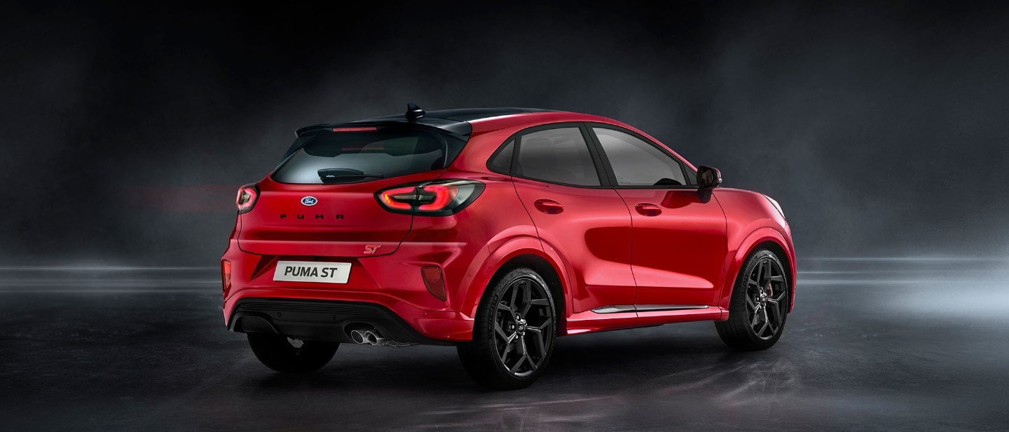 Ford Puma ST in Rot. 3/4-Heckansicht stehend in einem dunklen Showroom