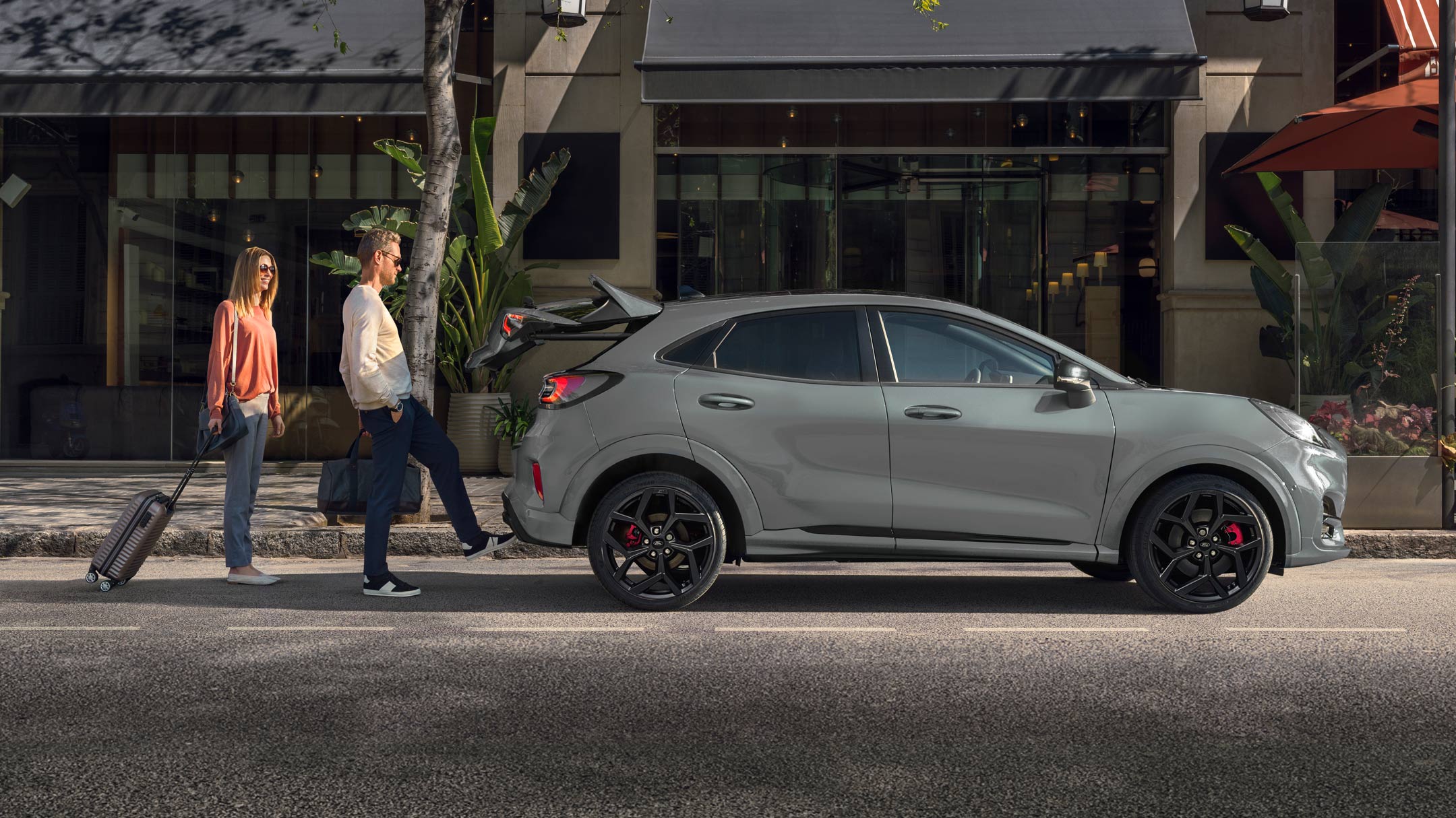 Ford Puma ST in Grau. Nahe Seitenansicht, ein Mann öffnet die sensorgesteuerte Heckklappe per Fußbewegung