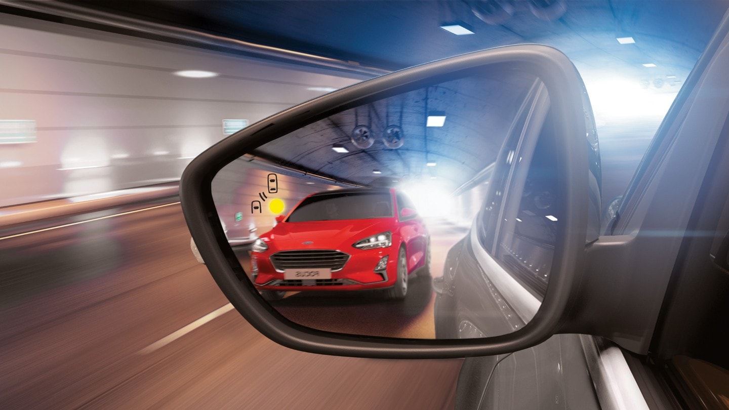 Ford Puma ST in Grau. Detailansicht des Außenspiegels mit rotem Ford Focus im Hintergrund