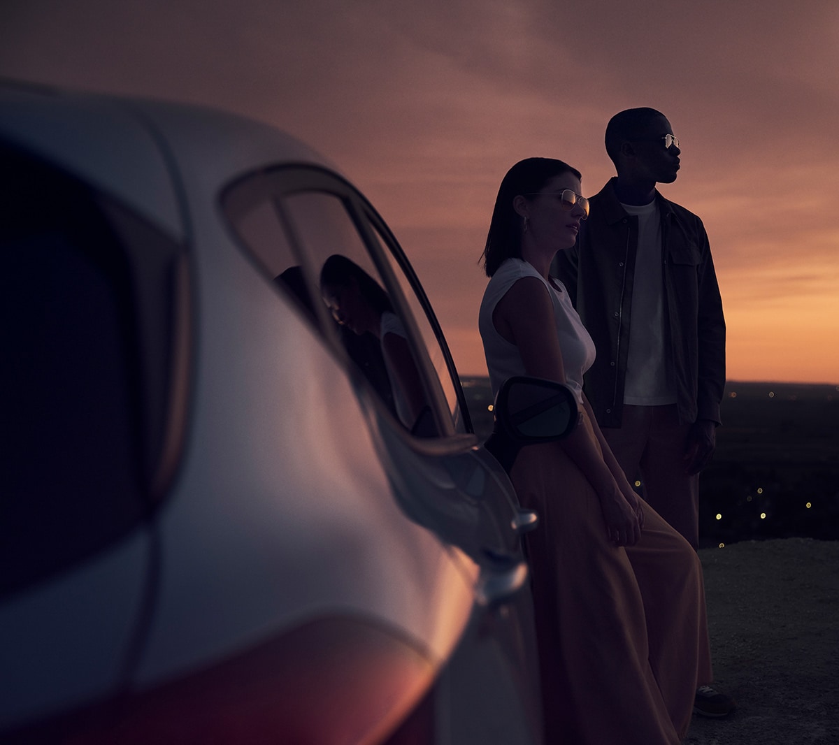Ford Fiesta in Blau. Heck-Detailansicht im Sonnenuntergang mit zwei Personen im Hintergrund.