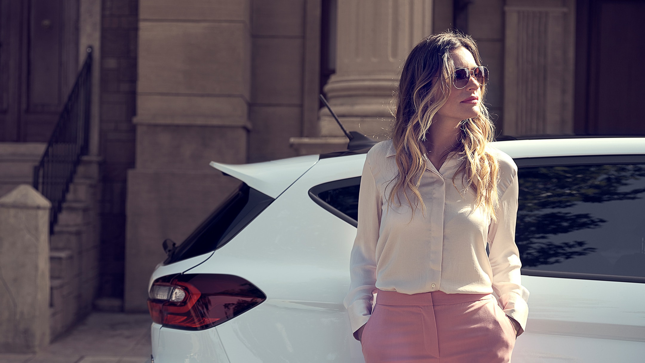 Ford Fiesta in Weiß. Seitenansicht, eine Frau im Vordergrund.
