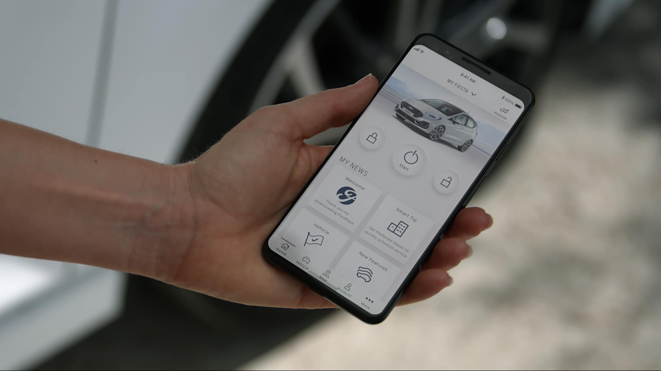FordPass App auf einem Smartphone vor einem weißen Ford Fiesta ST.