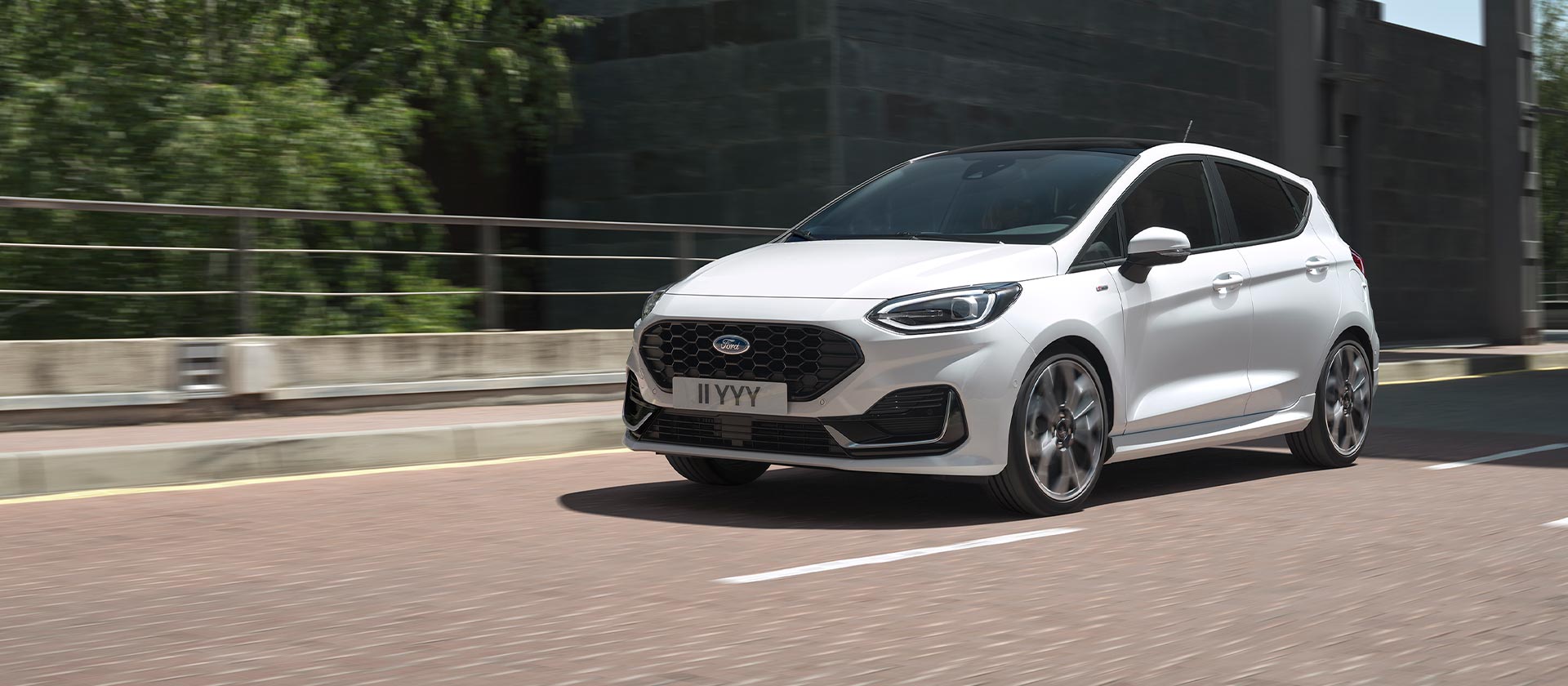 Weißer Ford Fiesta fährt in einer Stadt.