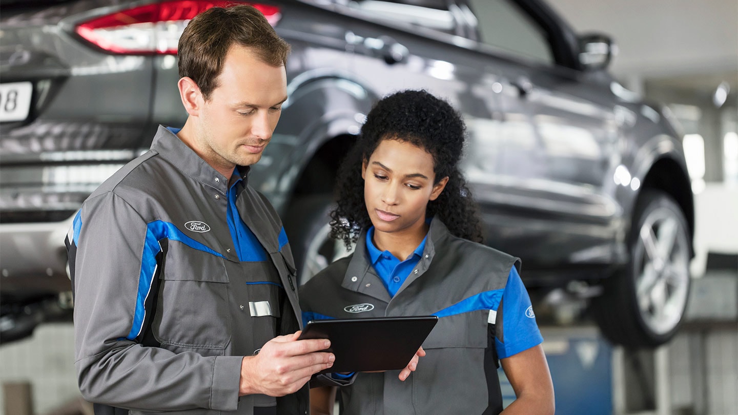 Zwei Ford-Reparaturspezialisten überprüfen ihr Online-Service-Buchungssystem am Telefon