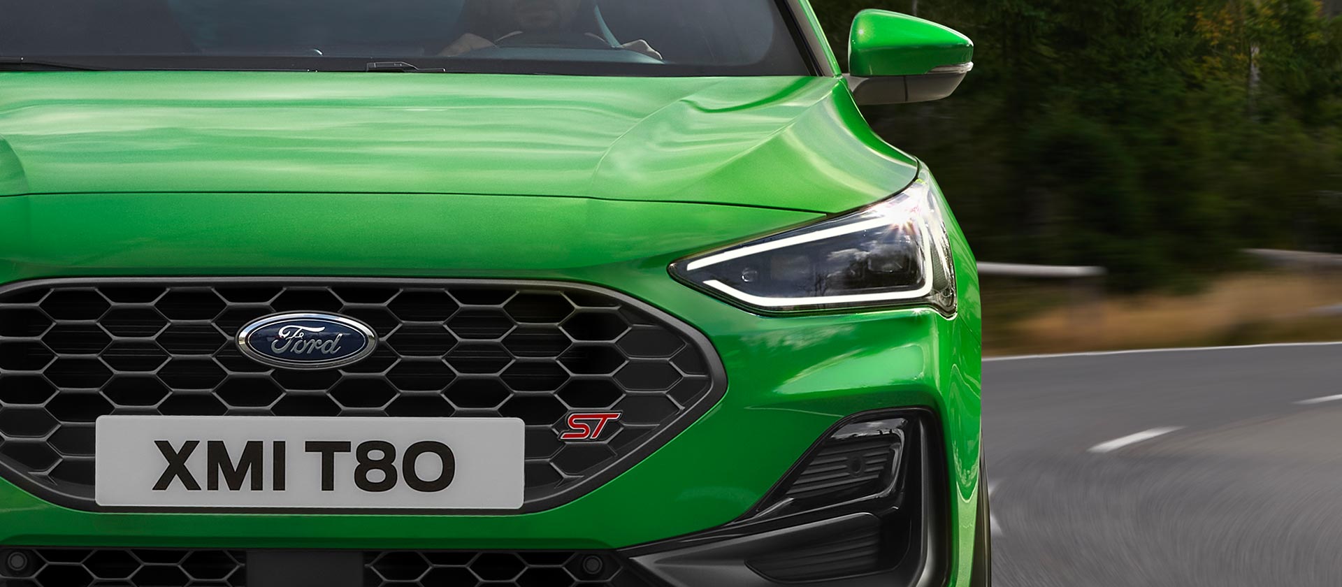 Eine Frontansicht des Ford Focus ST in Mean Green, die den Wabengrill und das ST-Emblem zeigt.