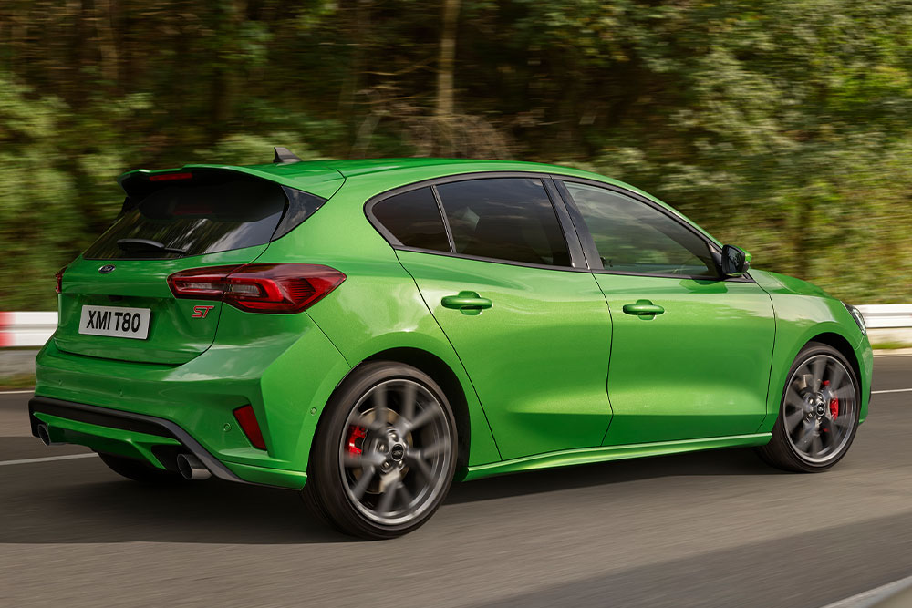 Rückansicht eines Ford Focus ST Schrägheck in Mean Green, der auf einer Rennstrecke fährt.