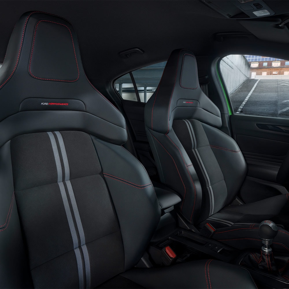 Eine Nahaufnahme der Ford Focus ST Sportsitze mit dunkler Polsterung und roten Kontrastnähten.