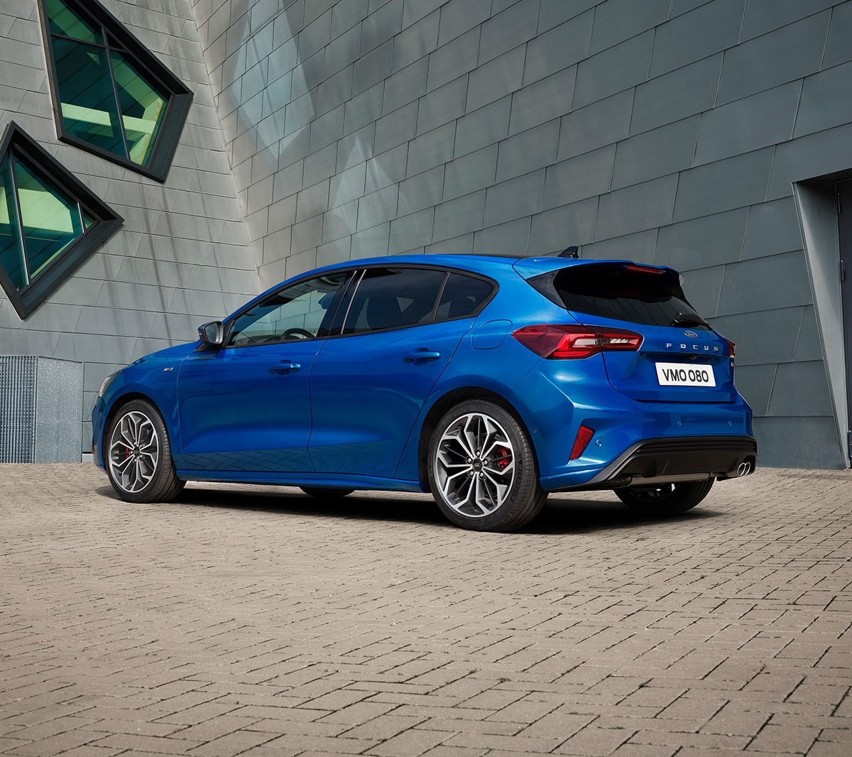 Ford Focus in Blau. Dreiviertel-Heckansicht, vor einem modernen Gebäude parkend.