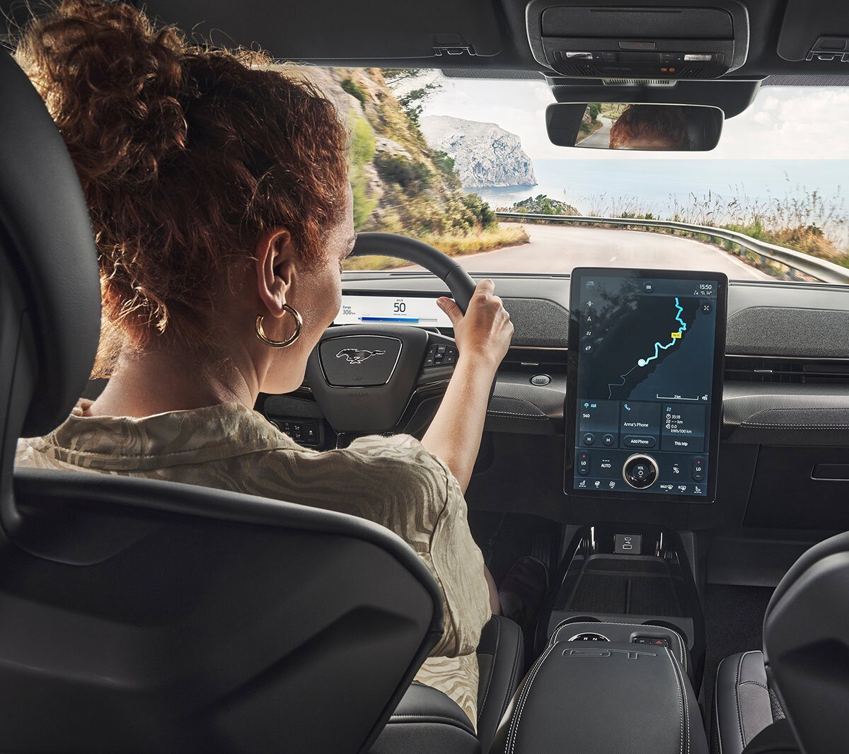 Ford Mustang Mach-E GT. Innenraumansicht, eine Frau betrachten den Ford SYNC 4 Touchscreen.
