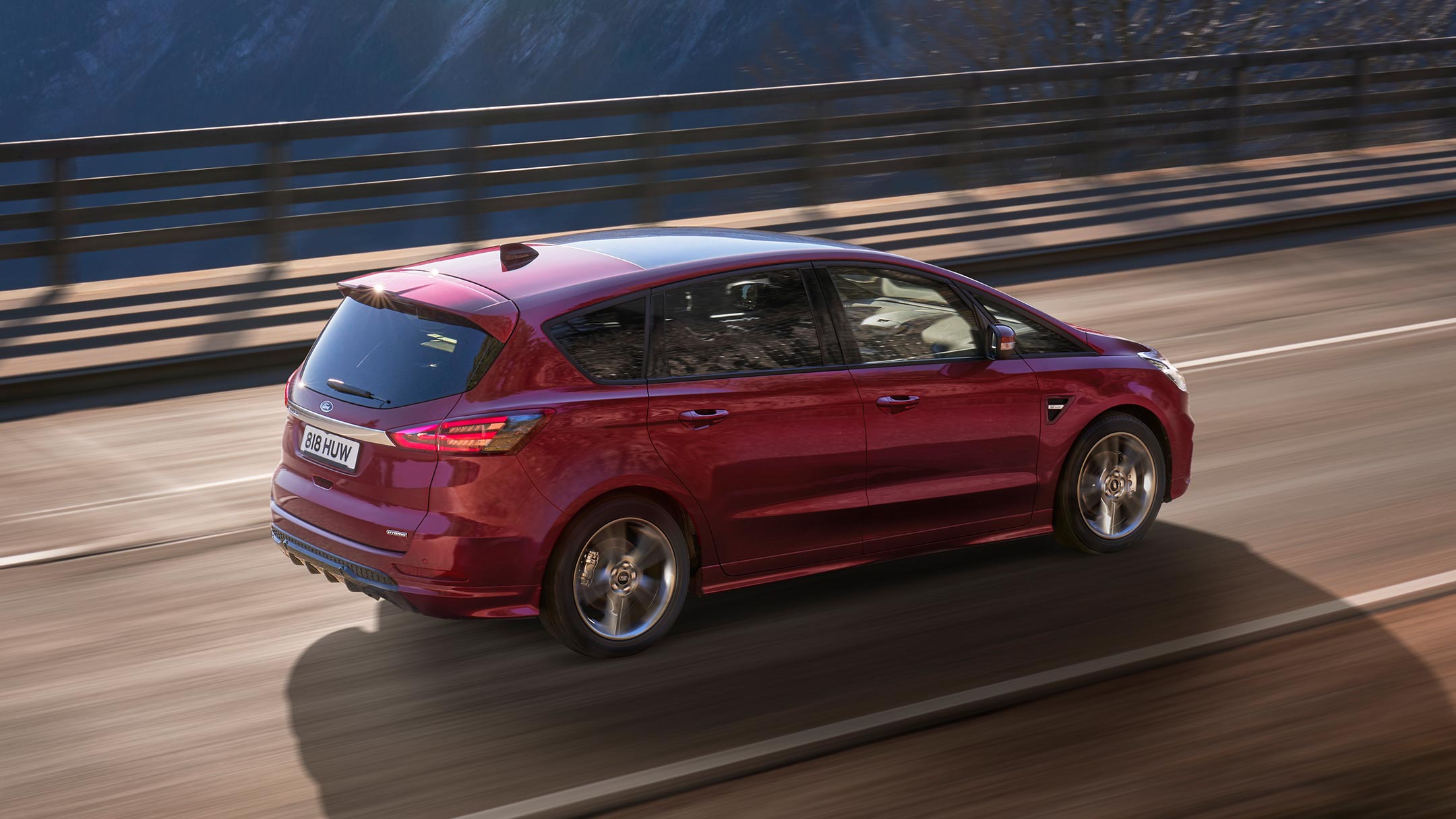 Ford S-MAX Hybrid in Rot. Dreiviertel-Heckansicht, auf einer Brücke fahrend
