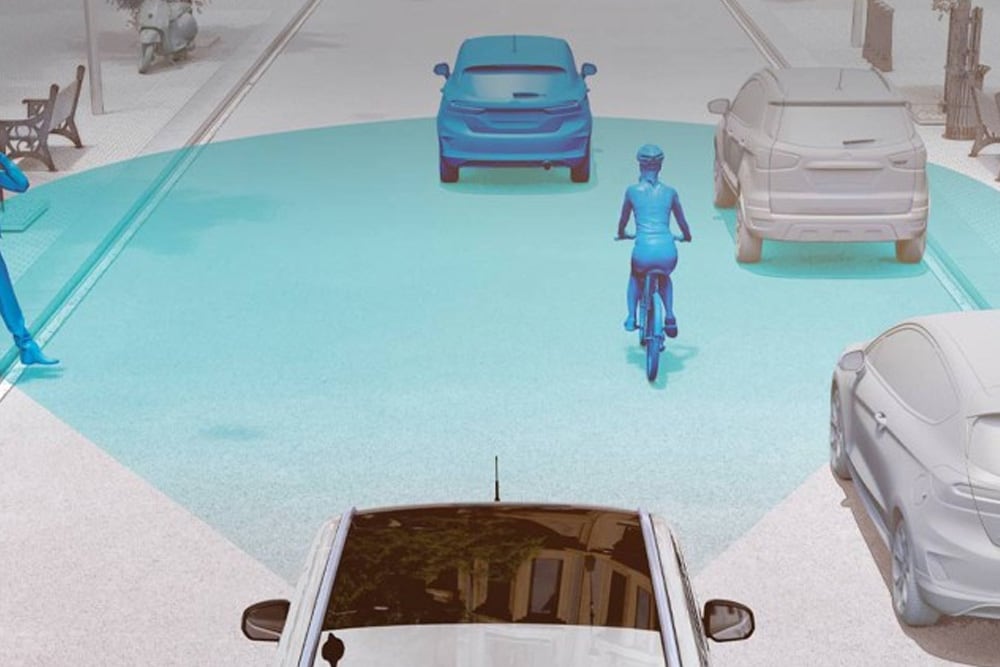 Grafik, die ein Fahrzeug aus der Vogelperspektive zeigt, wie es mit Sensoren den Verkehr, einschließlich eines Radfahrers, erfasst.