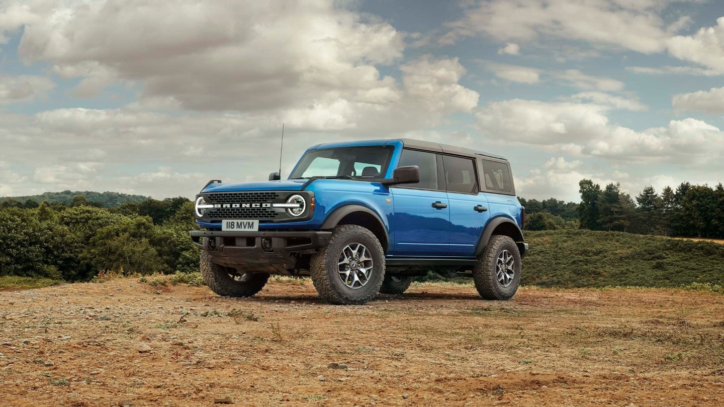 Ford Bronco in Blau, in 3/4-Frontansicht auf sandigem Untergrund stehend