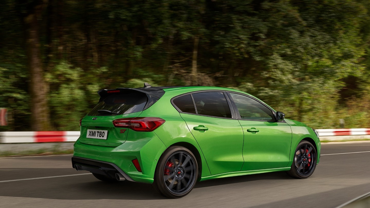 Ford Focus ST in Grün. Dreiviertel-Rückansicht, auf einer Straße fahrend.